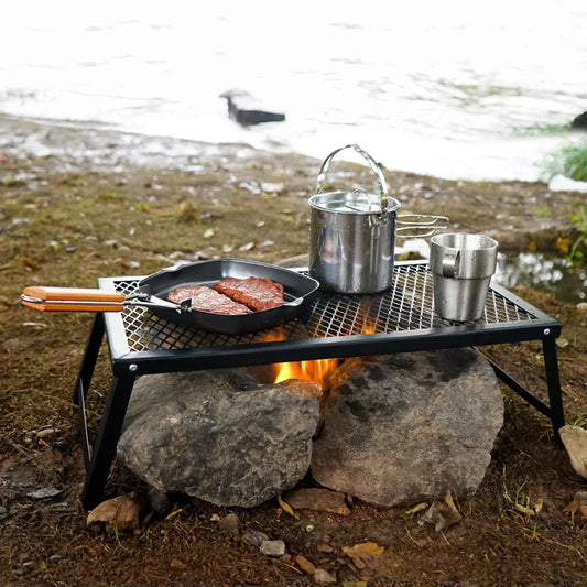 Outdoor camping scene with cooking setup by a body of water